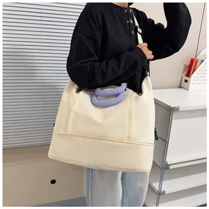 Vista dettagliata della grande borsa da viaggio beige con manici viola e design espandibile.