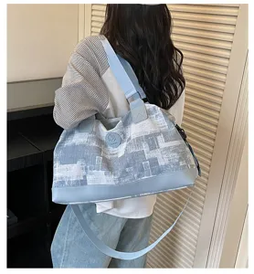 Detail view of stylish blue and white travel duffel bag with shoulder strap for women.