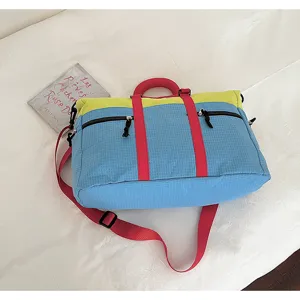 Detail view of color-block travel duffel bag with red straps and large capacity for sport.