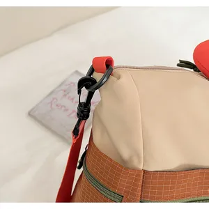 Bag detail shot showing contrast color block design, durable fabric, and sturdy black strap hook.