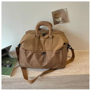 Detailaufnahme der braunen Canvas Reisetasche mit karierter Vordertasche und verstellbarem Gurt.