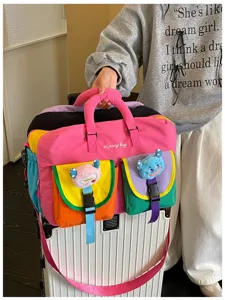 Colorblock travel fitness bag with multiple pockets and cute plush monster pendants for outdoor use.