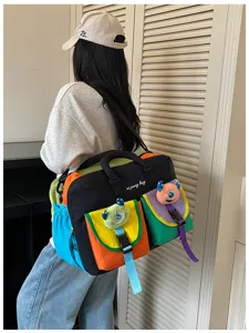 Detail view of colorful color-blocking travel gym yoga duffel bag with cute monster charms.