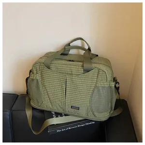 Gros-plan sur le sac de voyage à carreaux verts montrant la texture et la poche en filet.