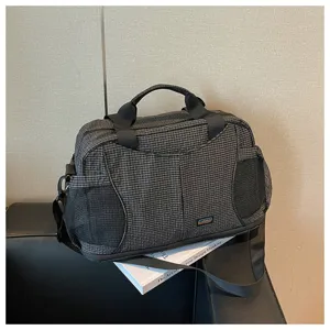 Grand sac de voyage et de sport à carreaux avec bandoulière et poches latérales en filet.