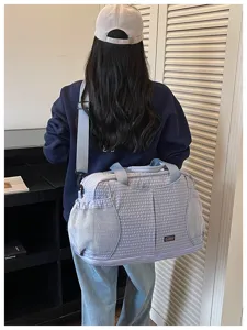 Vue détaillée du grand sac de voyage à carreaux avec poches en filet et bandoulière de sport.