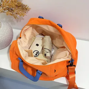 Grande borsa da viaggio arancione con manici blu e tracolla per sport e fitness in palestra.