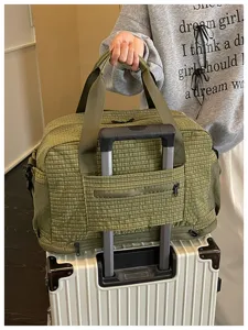Vue détaillée du sac de voyage vert à carreaux avec sangle pratique pour valise.