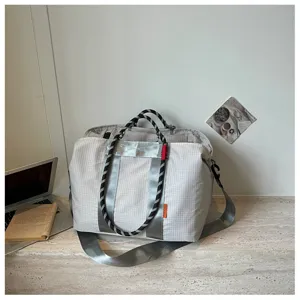Vue détaillée du sac de sport léger à carreaux montrant la sangle et la texture du tissu.