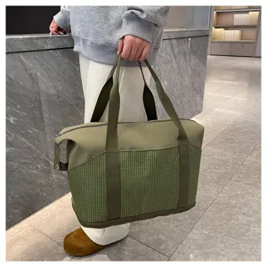 Vista dettagliata della borsa da viaggio verde in tela con motivo a quadri e manici robusti.