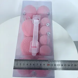 Detailed close-up of pink flocked Christmas ball ornaments in clear box with ruler for size.