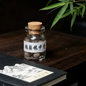 Detailed close-up of traditional handmade incense pills stored in a clear glass cork bottle.