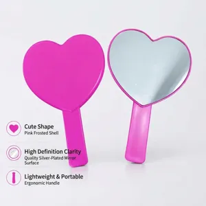 Miroir de maquillage portatif en forme de cœur rose avec poignée ergonomique et verre argenté.