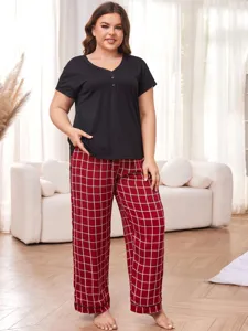 Plus size plaid pajama set showing short sleeve top and long pants in living room scene.