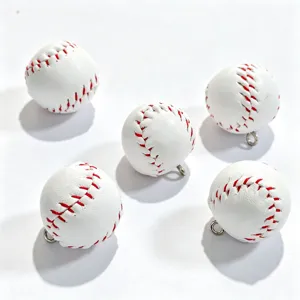 Vue détaillée de mini charms de baseball en PVC avec anneaux métalliques pour bijoux.