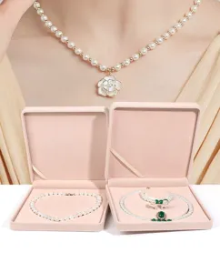 Detailansicht von luxuriösen rosa Samt Schmuckschatullen und eleganter Perlenkette.