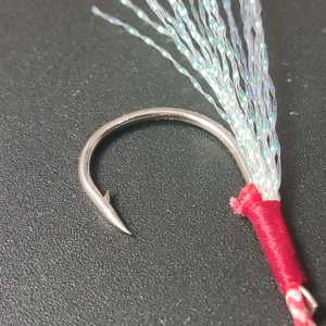 Close-up detail of fishing jig hook with flashing tinsel and red binding for sea lure fishing.