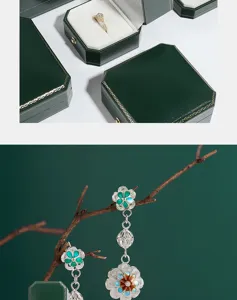 Detailed view of dark green octagonal jewelry boxes with gold trim and delicate enamel earrings.