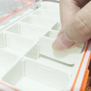 Portable plastic tackle storage box with adjustable dividers for small fishing gear parts.