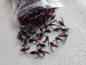 Set de anzuelos de pesca de moscas biónicos con diseño de plumas rojas y negras.