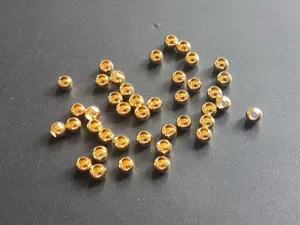 Detailed close-up shot of small golden metal beads, copper stop beads for fishing lure accessories.