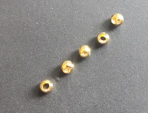 Close up detail of small gold metal beads, slotted copper positioning stoppers for fishing lines.