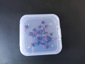 Detailed view of handmade fly fishing hooks lures set in transparent portable storage box.
