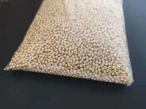 Detailed view of gold metal fishing beads, bulk copper spacer beads in transparent bag.