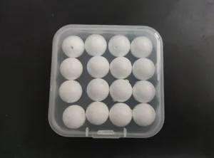 Close-up detail of 12mm white foam fishing float beads with center hole in plastic box.