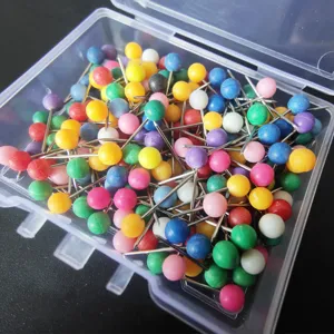 Chinchetas coloridas con cabeza de plástico en caja, ideales para oficina y manualidades.