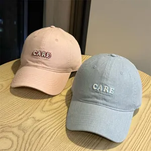Close-up view of casual cotton baseball caps with embroidered letters in soft pastel shades.