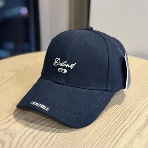 Detailed view of the dark cotton baseball cap featuring stylish front embroidery and brim text accents.
