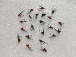 Detailed view of artificial fly fishing lures, simulation insect baits with red bead and feathers.