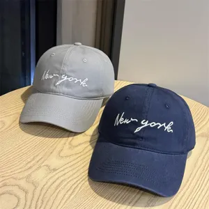 Detail shot of stylish embroidered baseball caps in grey and navy, featuring curved brim.