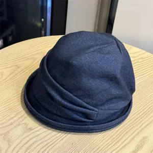 Close-up detail of the vintage dark blue denim pleated fisherman hat, showing soft texture.
