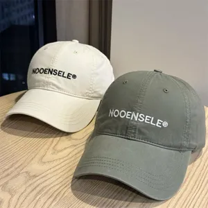 Detail view of stylish washed cotton baseball caps in beige and green with embroidery.