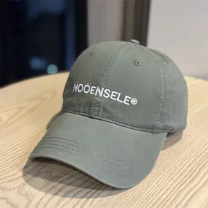 Close-up of stylish washed baseball cap with embroidered logo detail on wooden table surface.