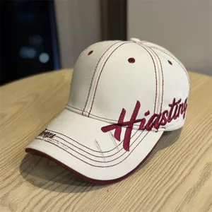 Detailed shot of retro beige baseball cap with maroon embroidery and stitching details.