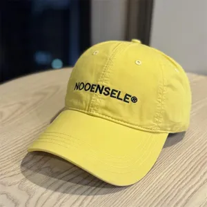 Close-up of yellow washed cotton baseball cap, embroidered curved brim hat detail.