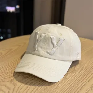 Off-white cotton baseball cap featuring 3D embroidered YY letters and curved brim style.