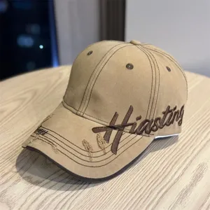 Close-up detail of retro embroidered baseball cap with distressed brim and bold front lettering.