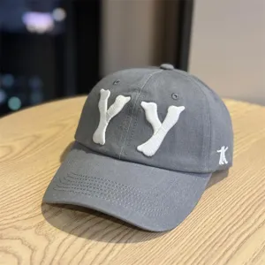 Close-up detail of the grey baseball cap featuring white 3D YY embroidery on the front.
