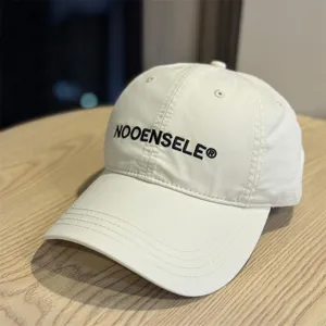 Minimalist washed cotton baseball cap with curved brim and embroidered lettering, casual.