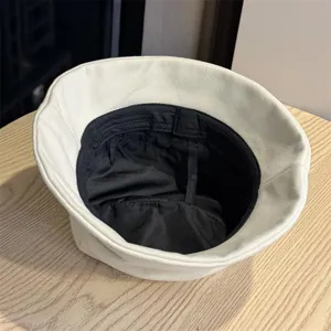 Minimalist pleated bucket hat detail shot showing black lining and solid color basin design.