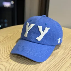 Close-up detail of the blue baseball cap with white 3D embroidered YY letters and side logo.