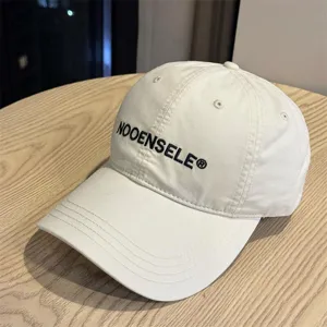 Close-up detail of the washed beige baseball cap featuring stylish front embroidery and curved brim.