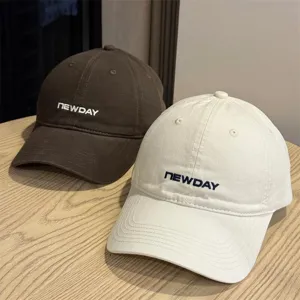 Detail view of retro washed cotton baseball caps in brown and beige with embroidery text.
