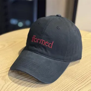 Closeup of black embroidered baseball hat with red formed lettering detail product.