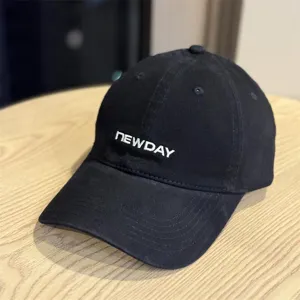 Close-up detail of a black washed cotton baseball cap with embroidered front lettering.