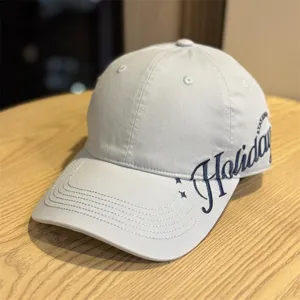 Nahaufnahme einer hellgrauen Baseballkappe mit seitlicher Stickerei und breiter Krempe.